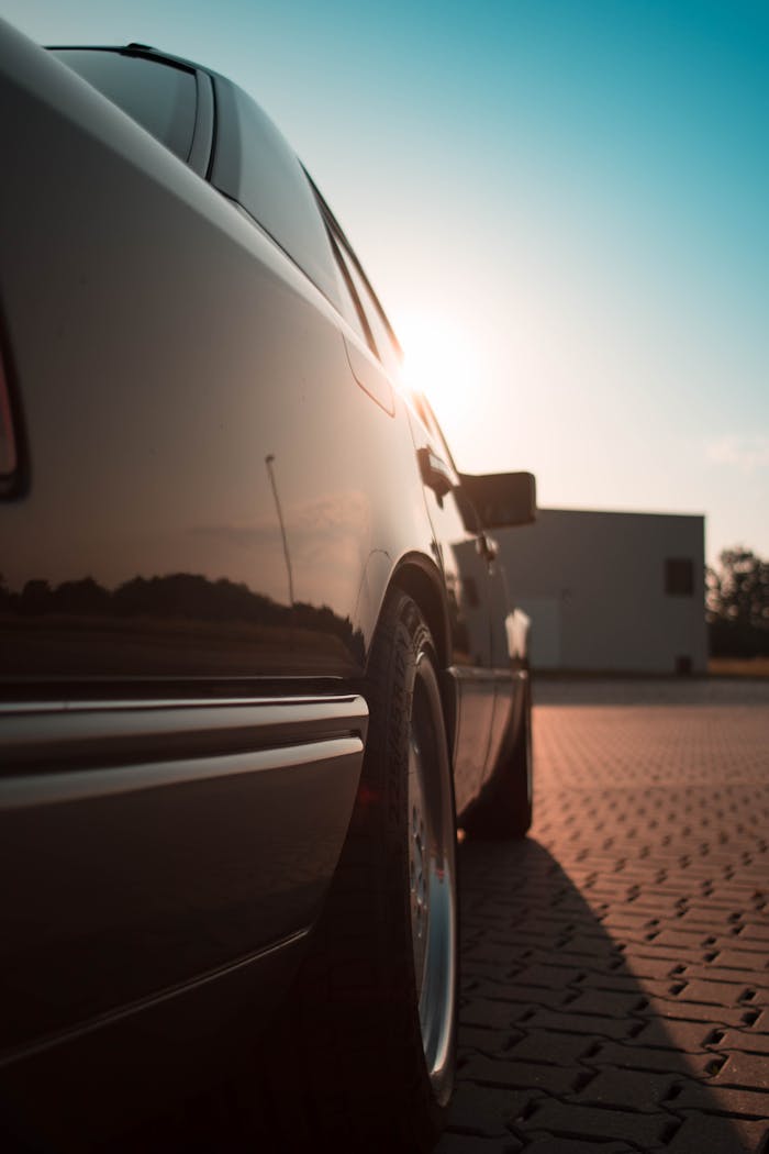 A parked sedan reflects sunlight on a paved surface during the day, highlighting automotive design.