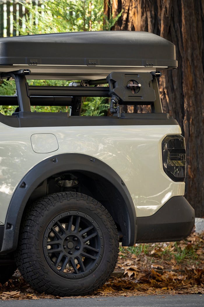 Off-road vehicle with rooftop cargo box in a nature setting, ideal for travel and adventure.