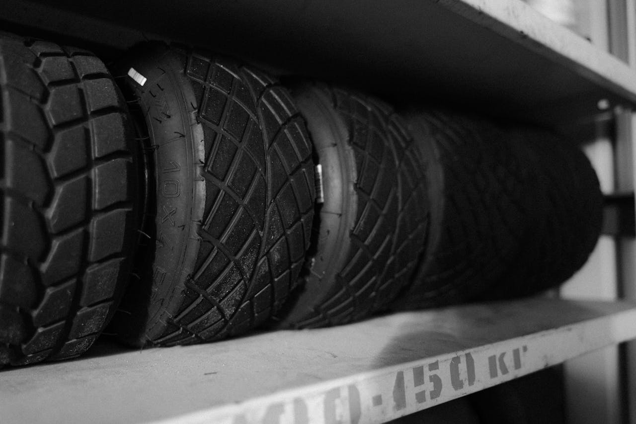 Monochrome photo of multiple tires arranged neatly on a shelf in a close-up shot.