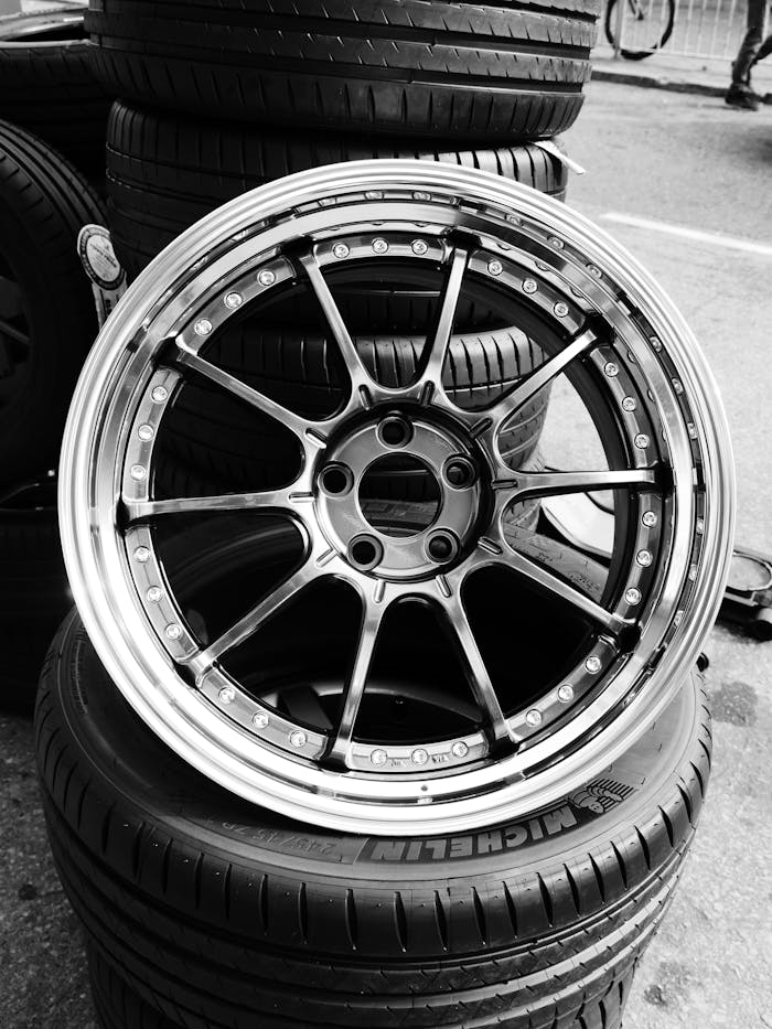 Monochrome photo of stacked car wheels with an alloy rim, emphasizing the tread design.