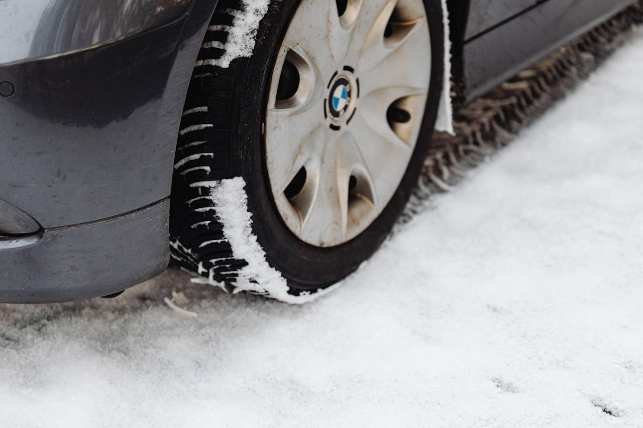Close-up of a car's tire on a snowy road, highlighting the winter season conditions.